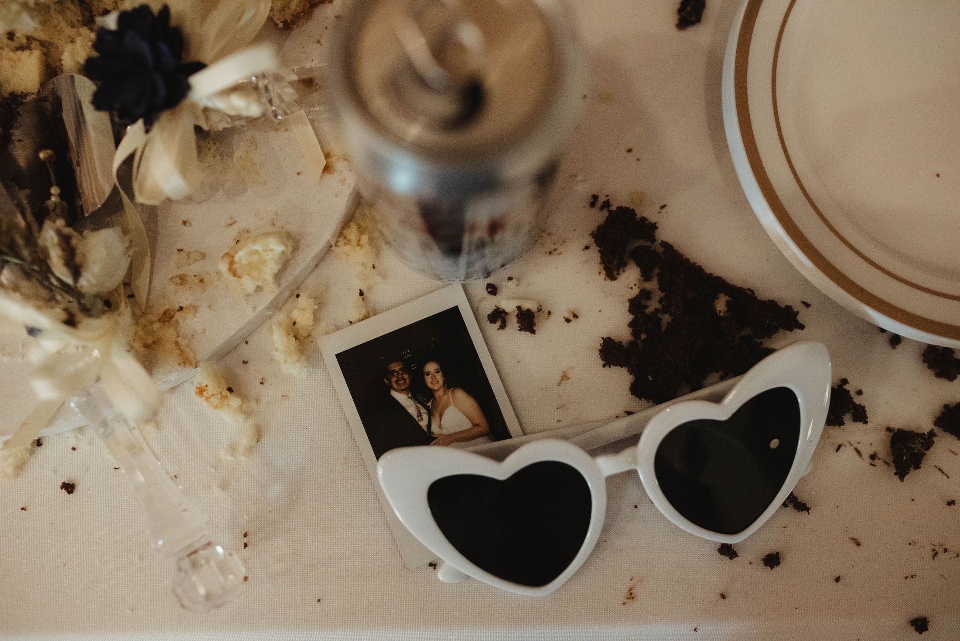 Sunglasses, photo, and cake crumbs on a messy table.