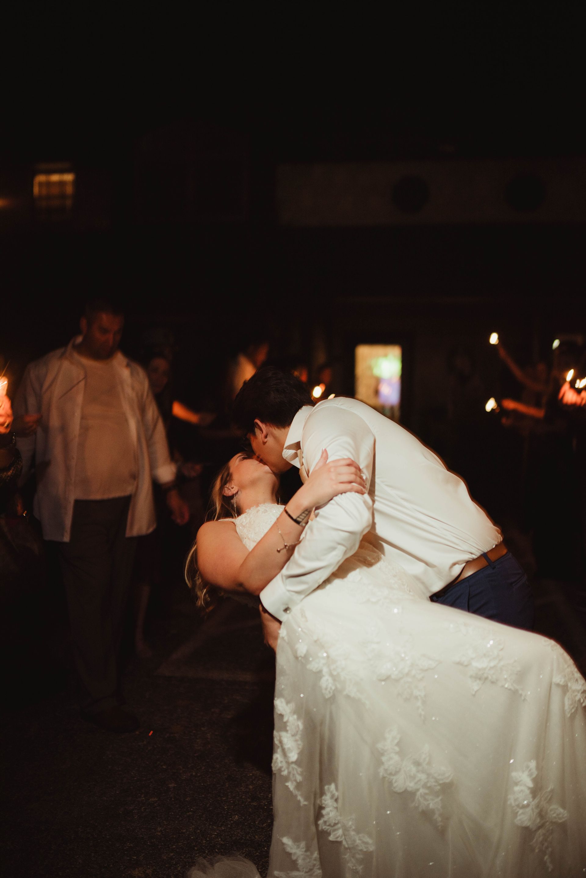 Couple kissing and dancing at night, woman in a white wedding dress.