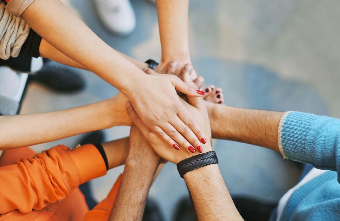A group of people are putting their hands together in a circle.