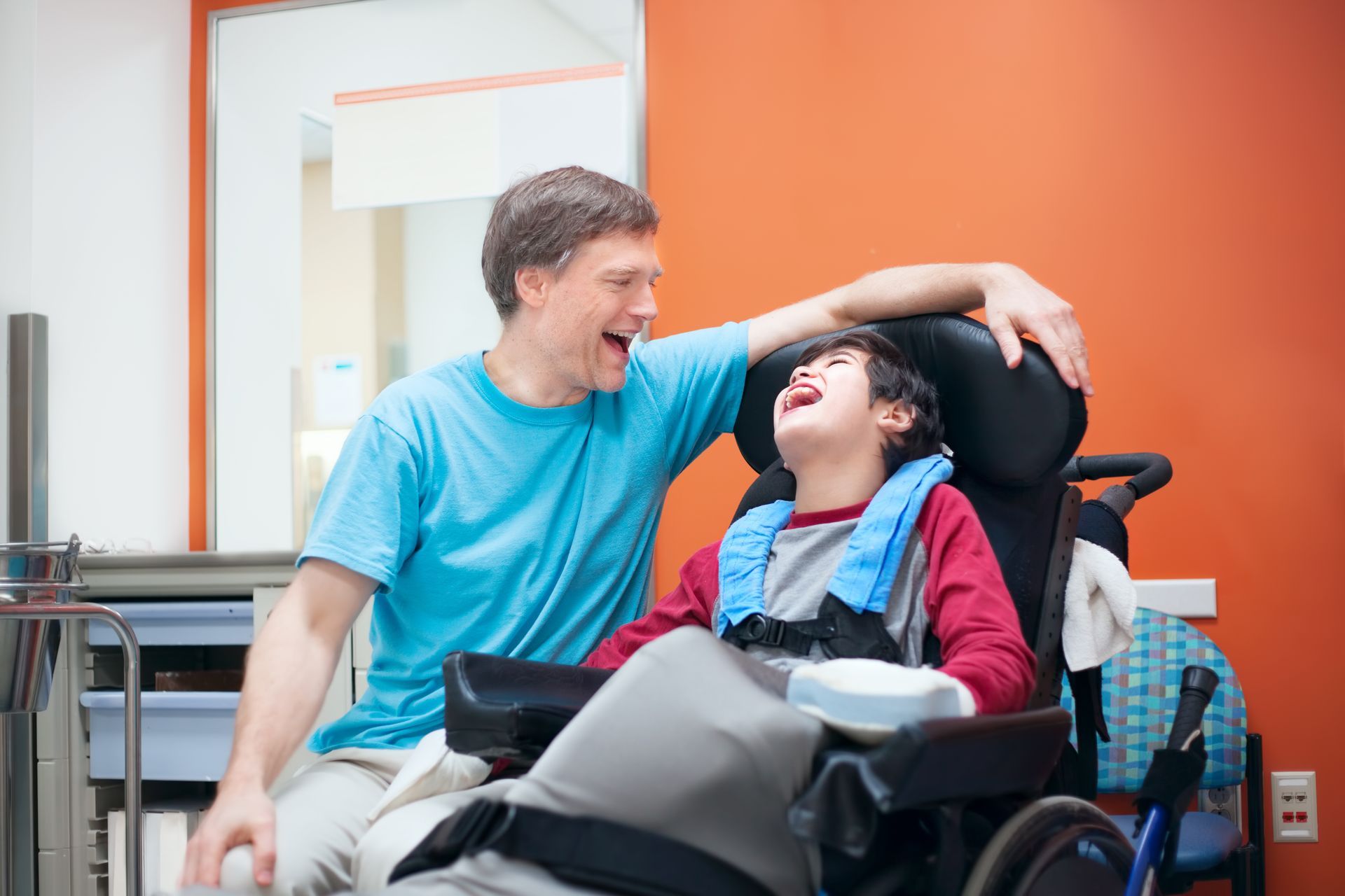 A man is sitting next to a boy in a wheelchair.