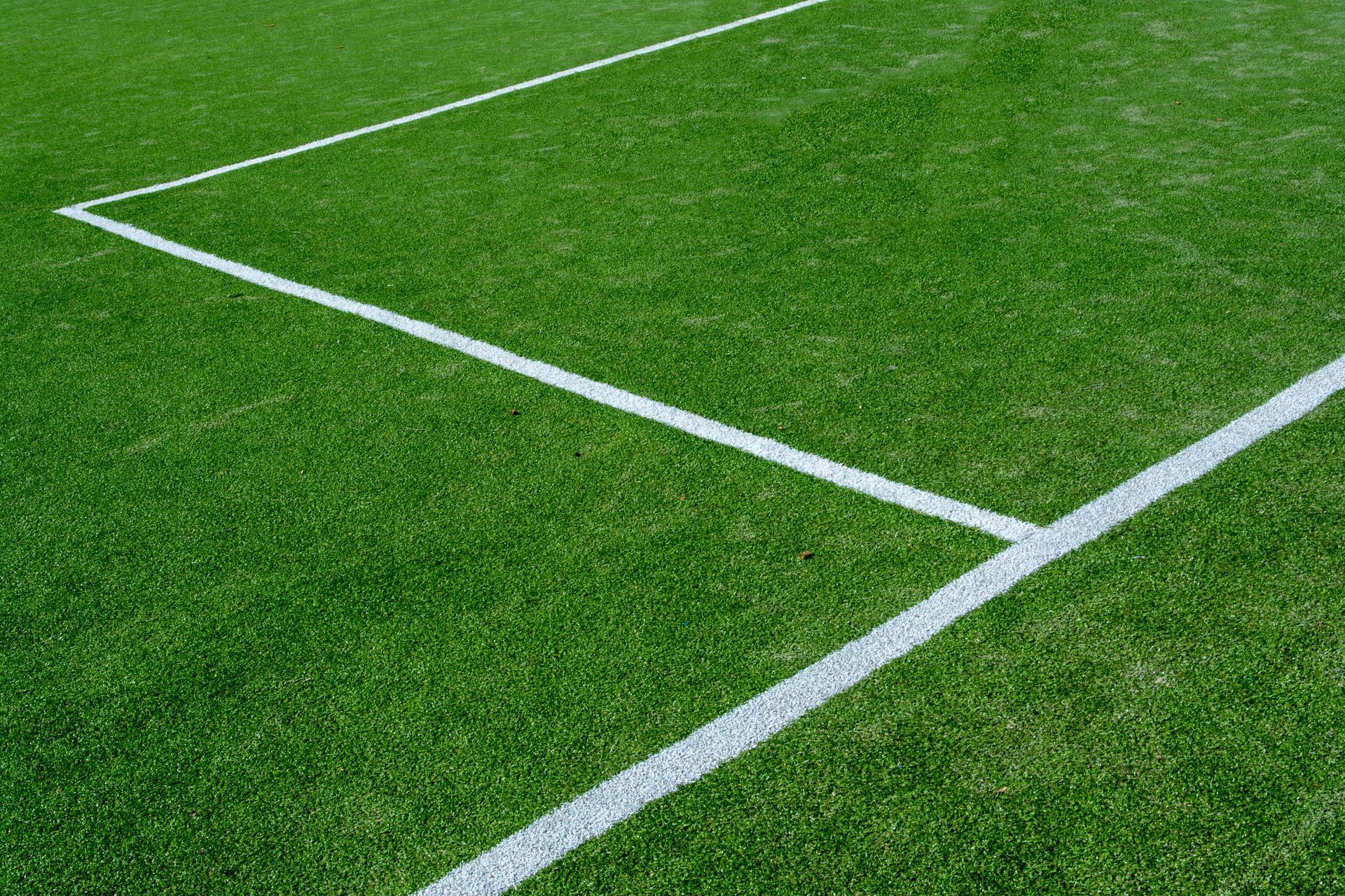 Green sports field corner with white boundary lines on artificial turf