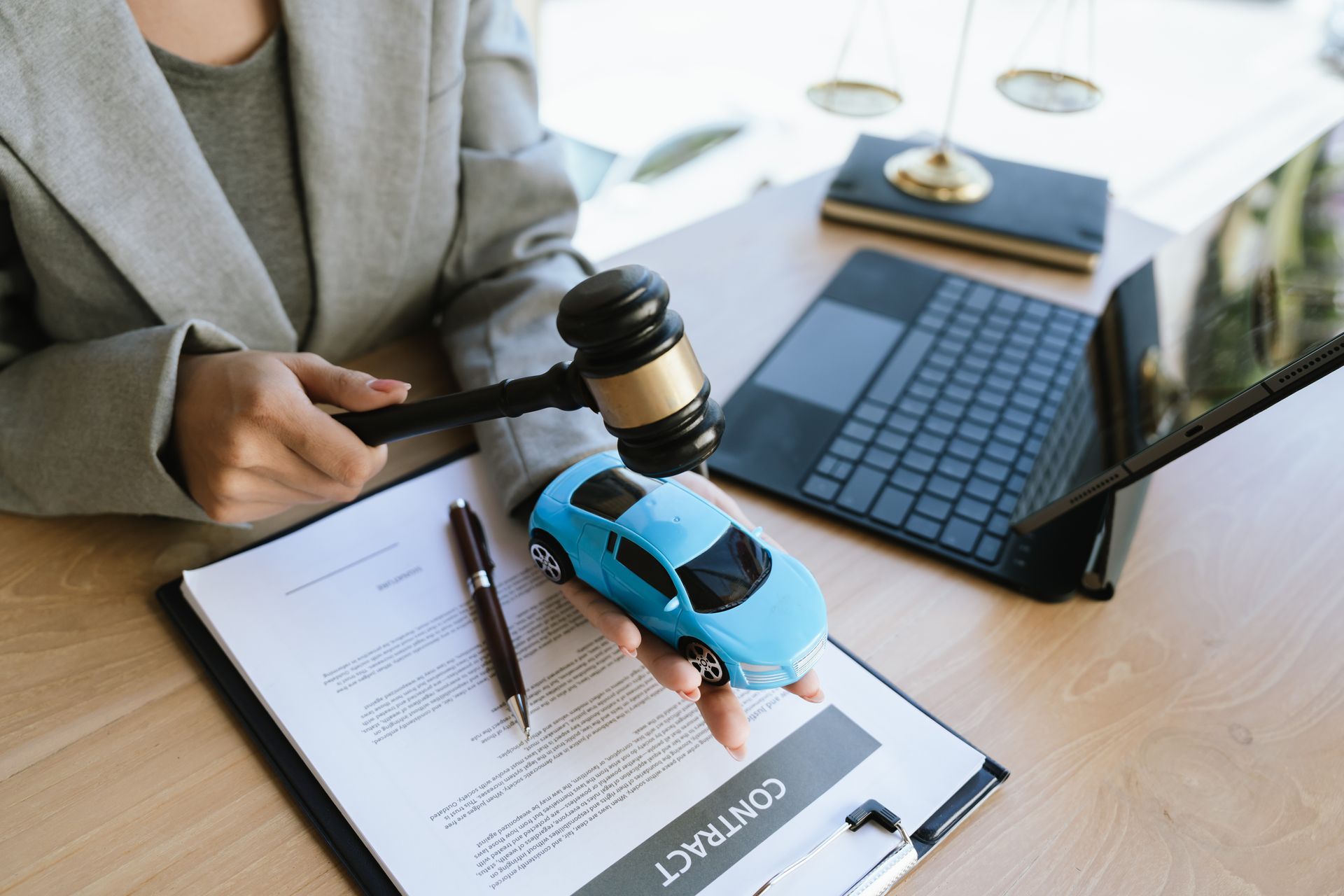 A lawyer signing a car contract with a gavel and a toy car on the desk. A lawyer signing a car contract with a gavel and a toy car on the desk.