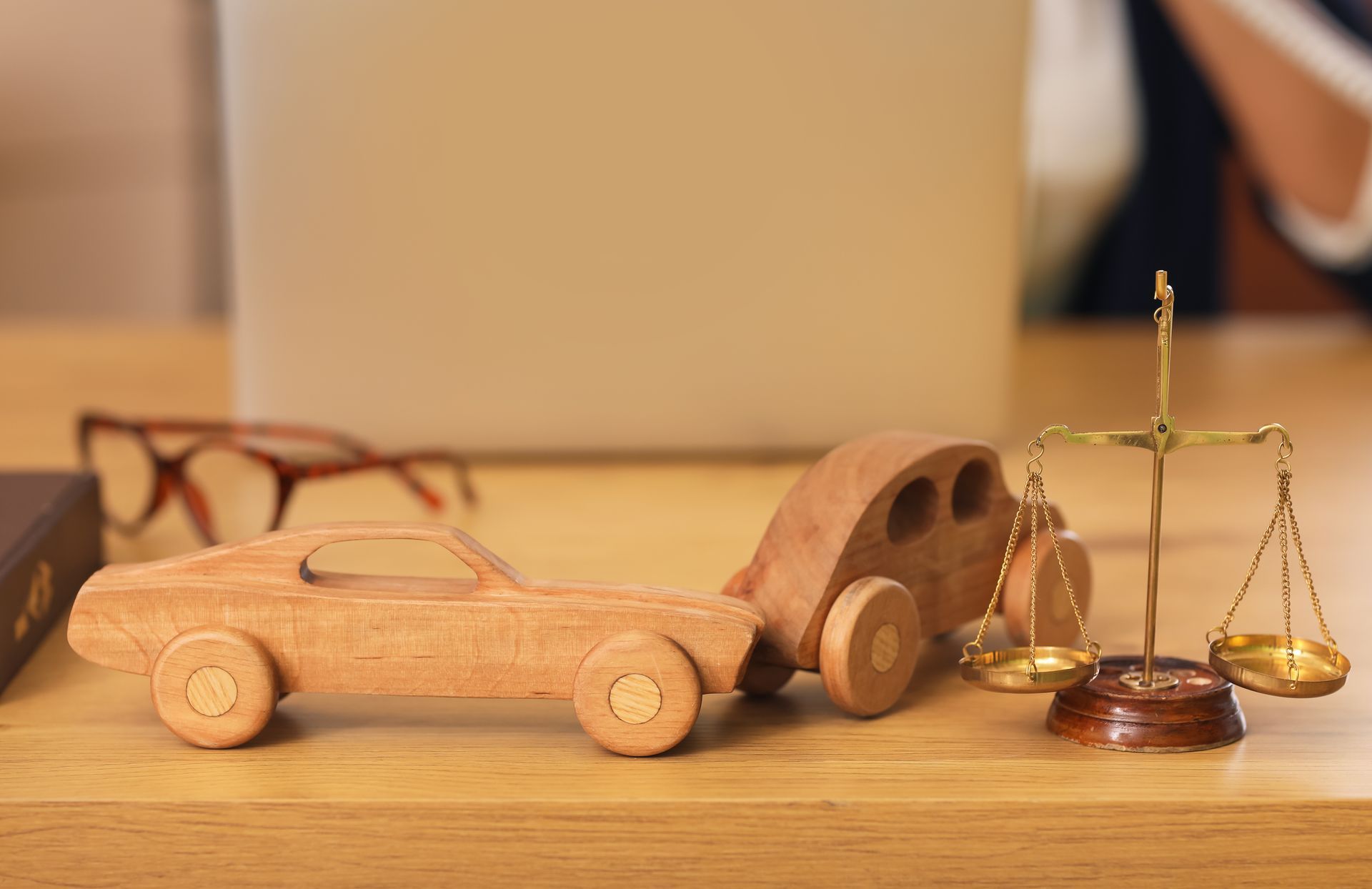 Justice scales with wooden cars on lawyer's table in office.