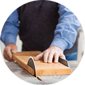 Person using a circular saw to cut a wooden board in a workshop.