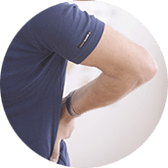 Person bending over, touching their lower back, wearing a navy blue shirt; light background.