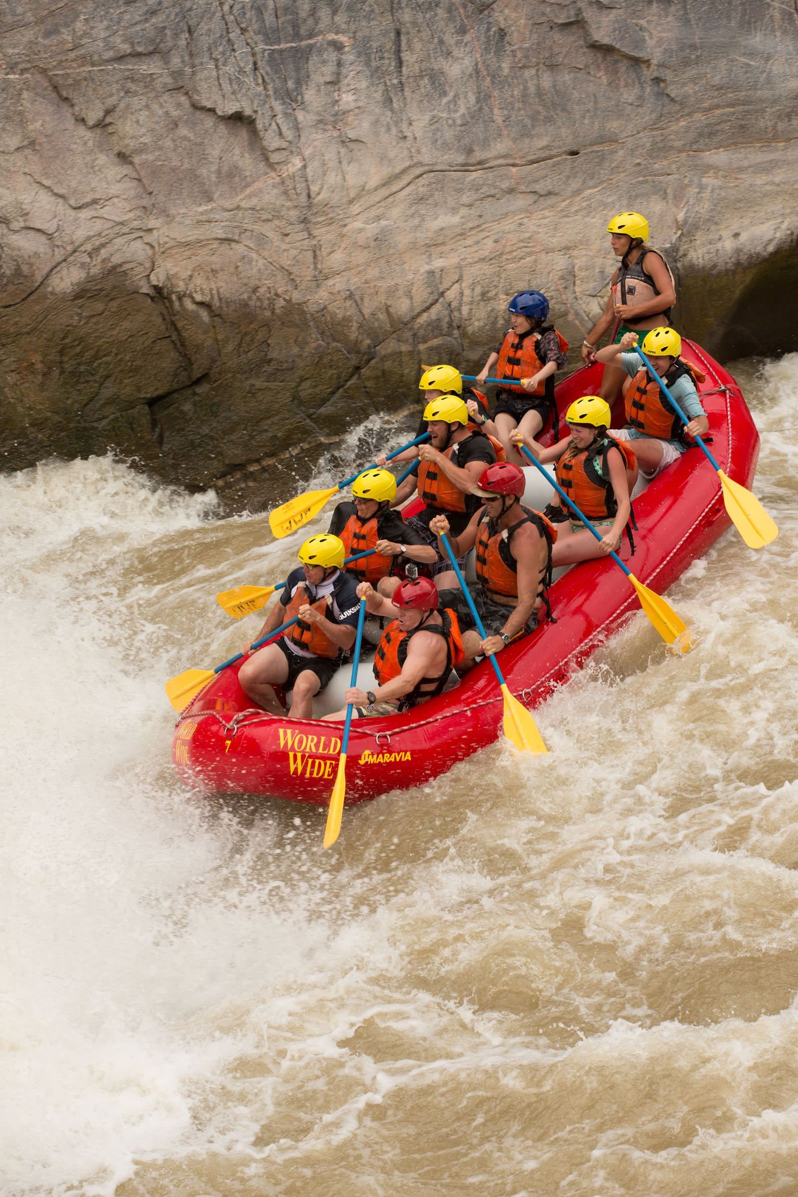 A group of people are rafting down a river in a red raft.