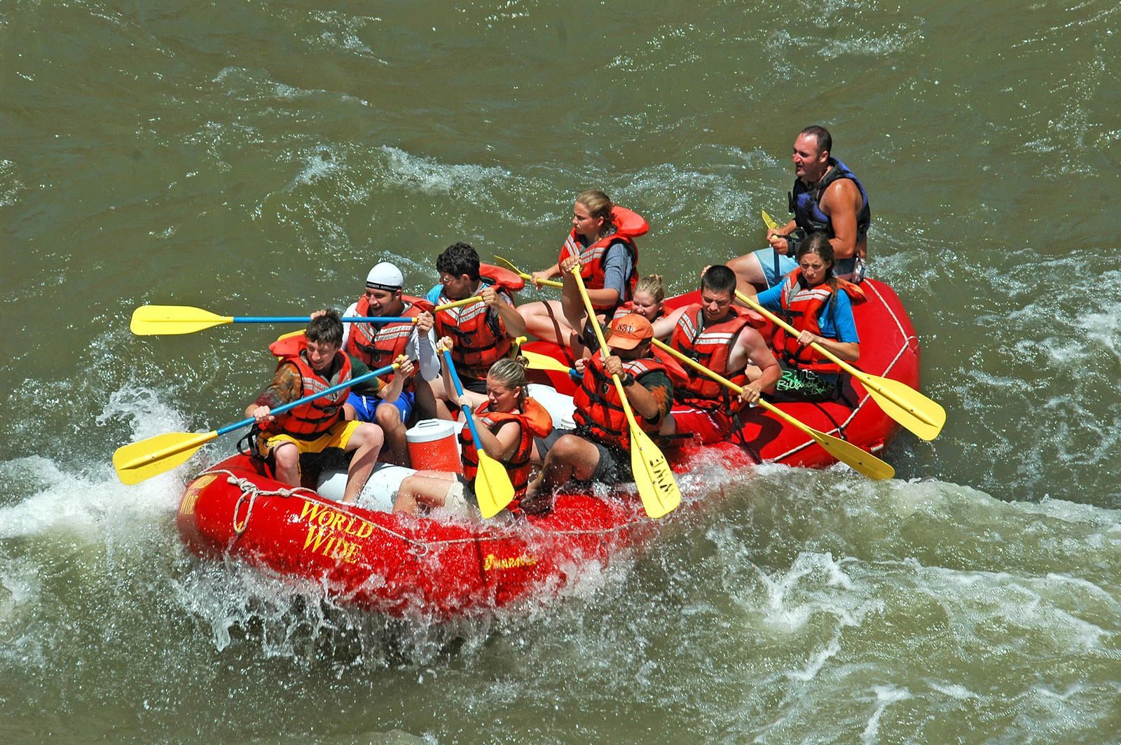 A group of people are rafting down a river in a red raft