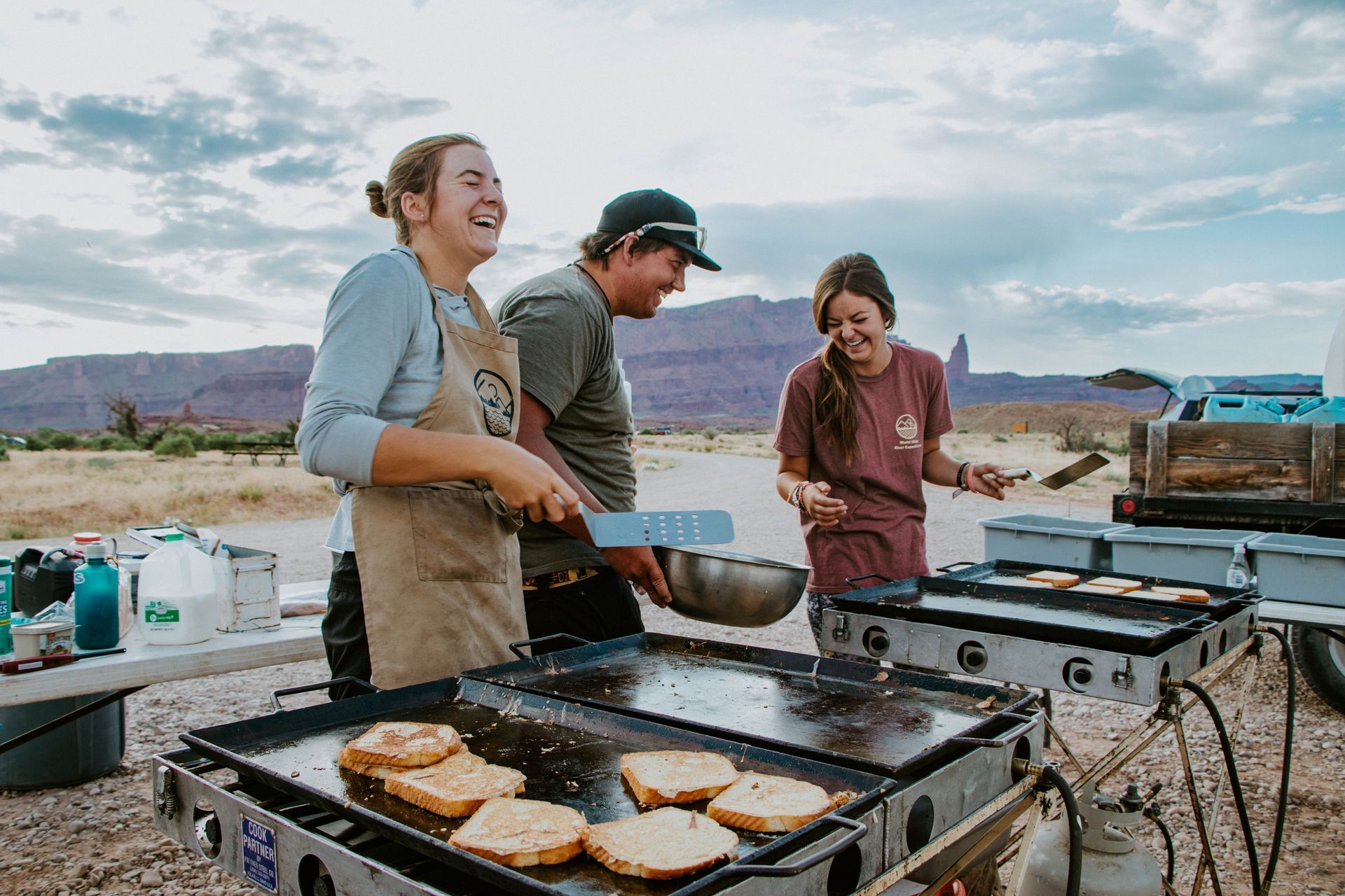 A group of people are cooking food on a grill in the desert.