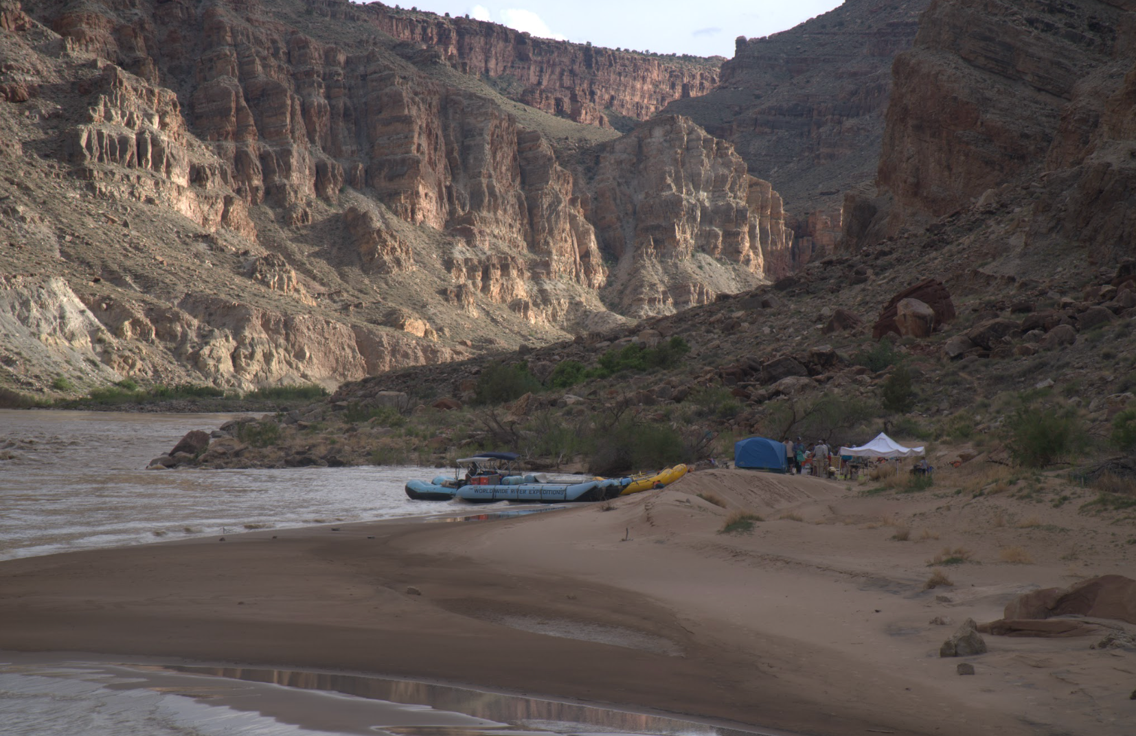 A couple of kayaks are sitting on a sandy beach next to a river.