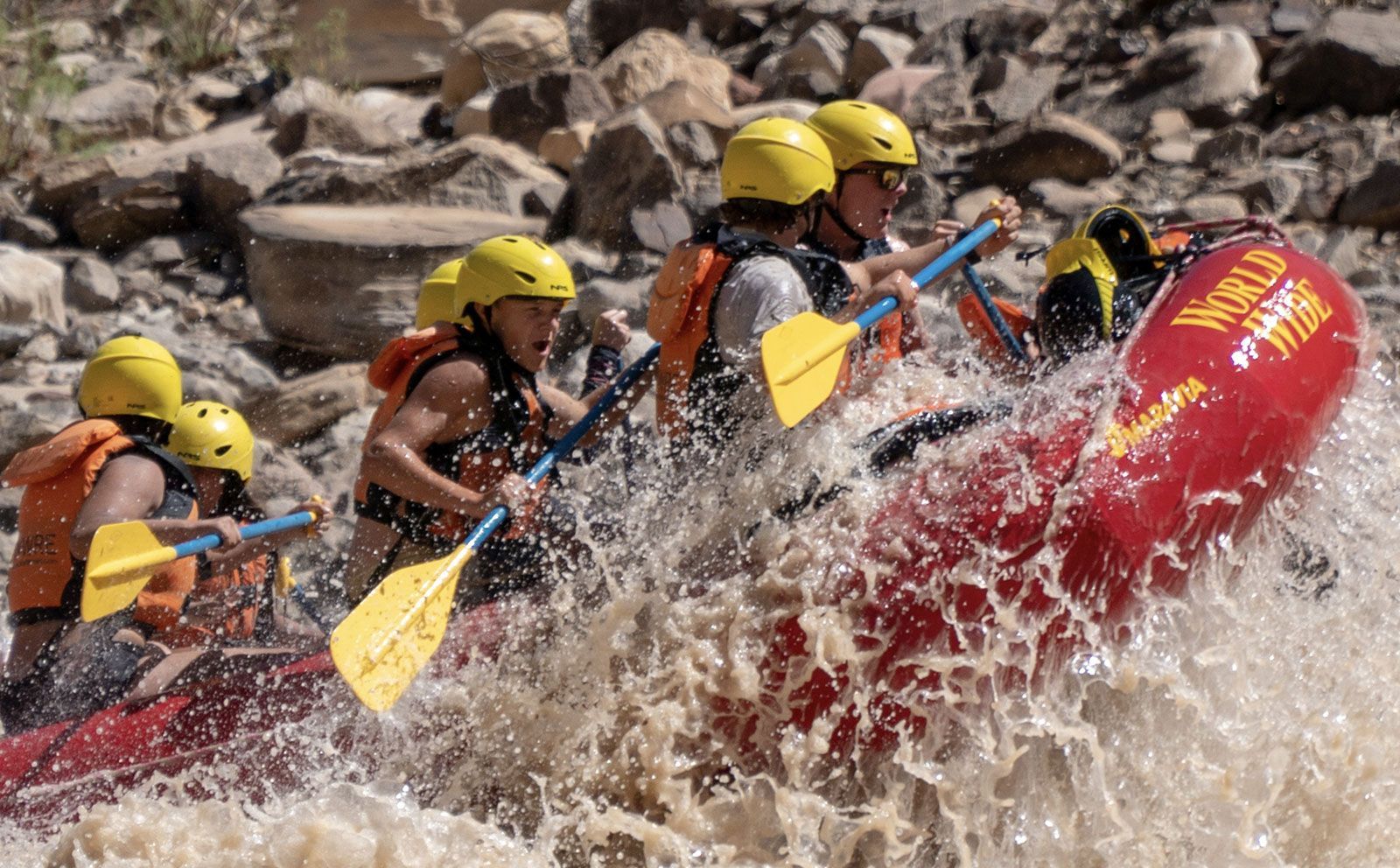 A group of people are rafting down a river in a red raft.