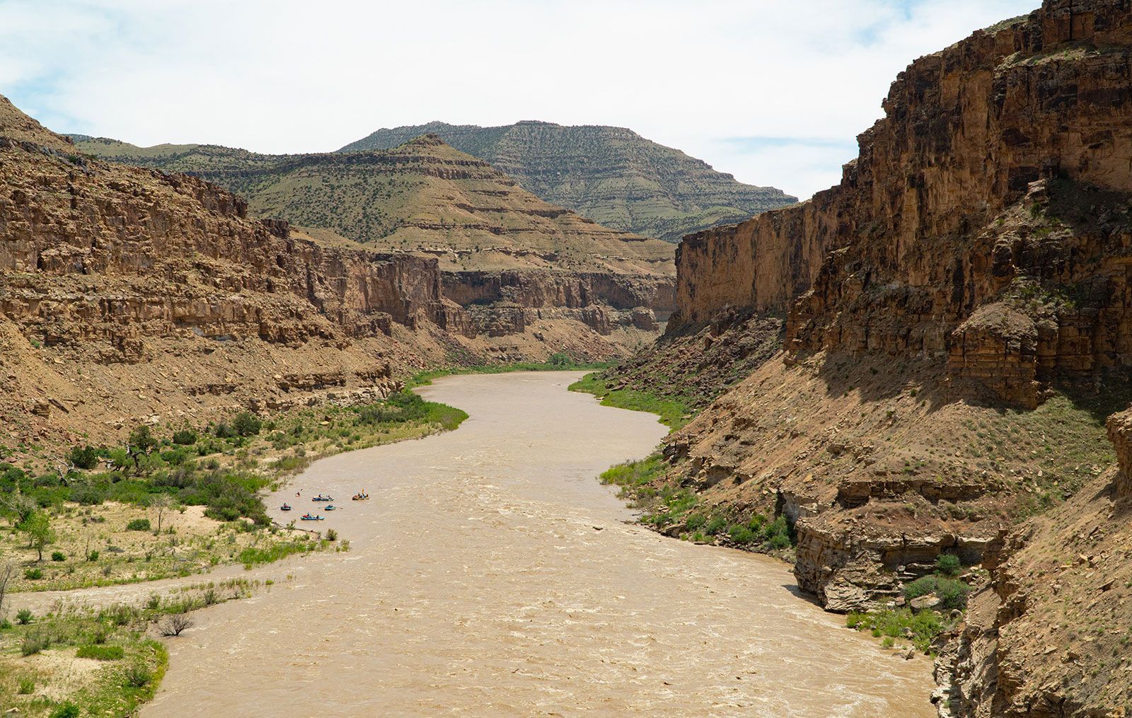 A river in the middle of a canyon with mountains in the background
