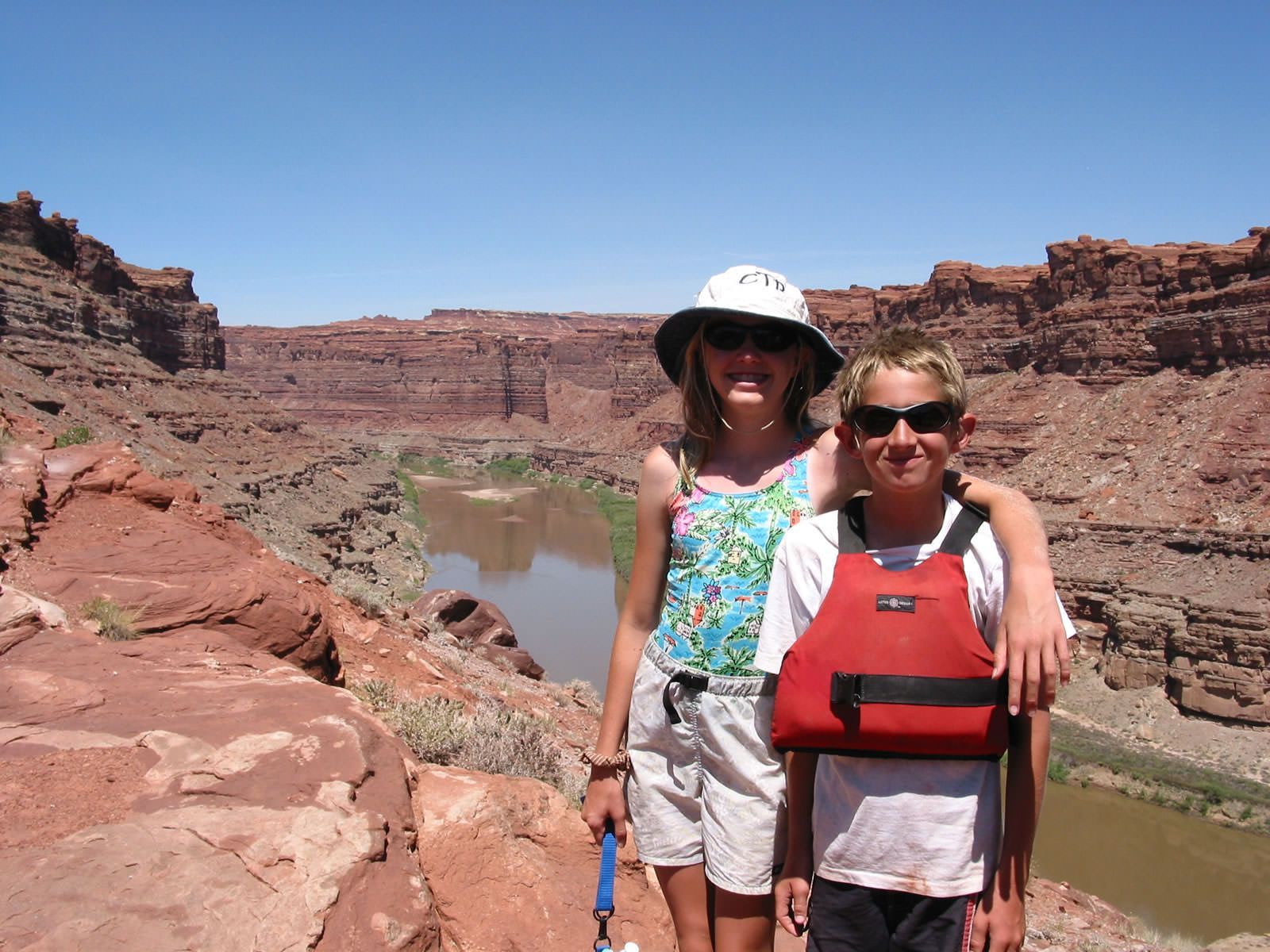 A boy and a girl are posing for a picture in front of a river