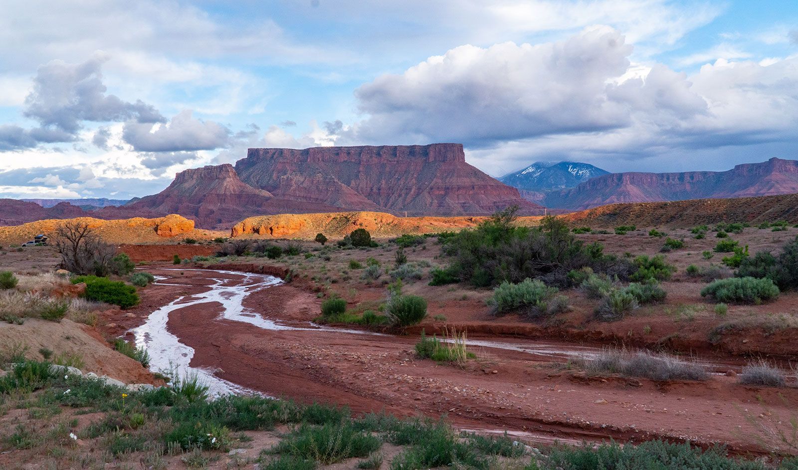 A river running through a desert landscape with mountains in the background.