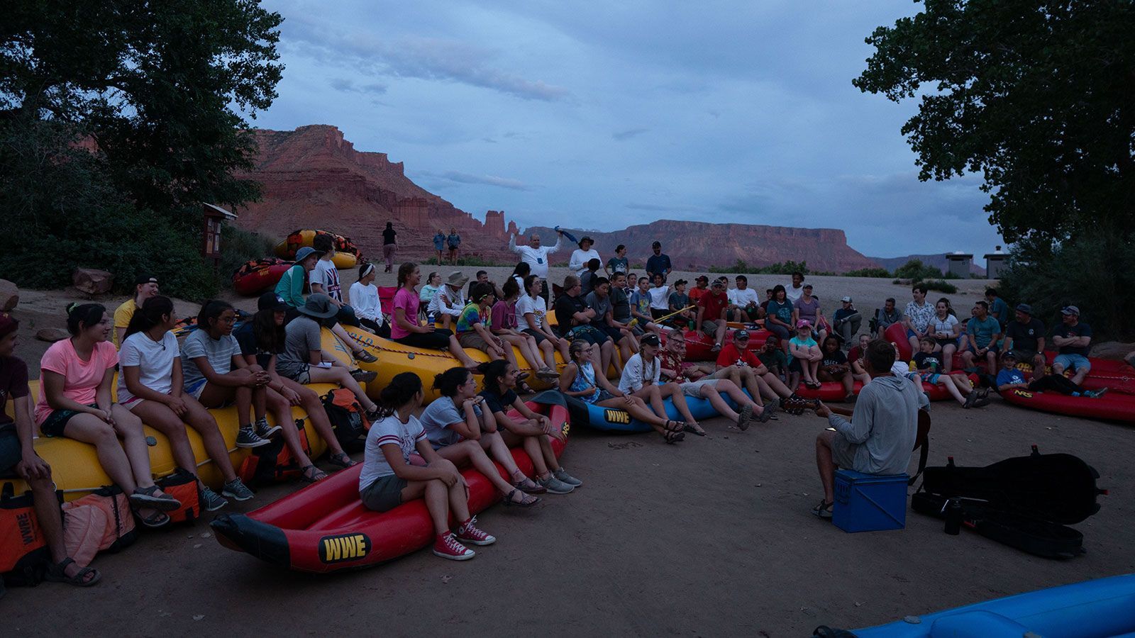 A group of people are sitting on rafts in the sand.