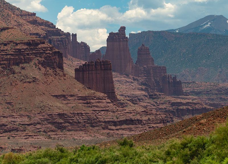 Red rock formations rise from a desert valley in a sunny, arid landscape.