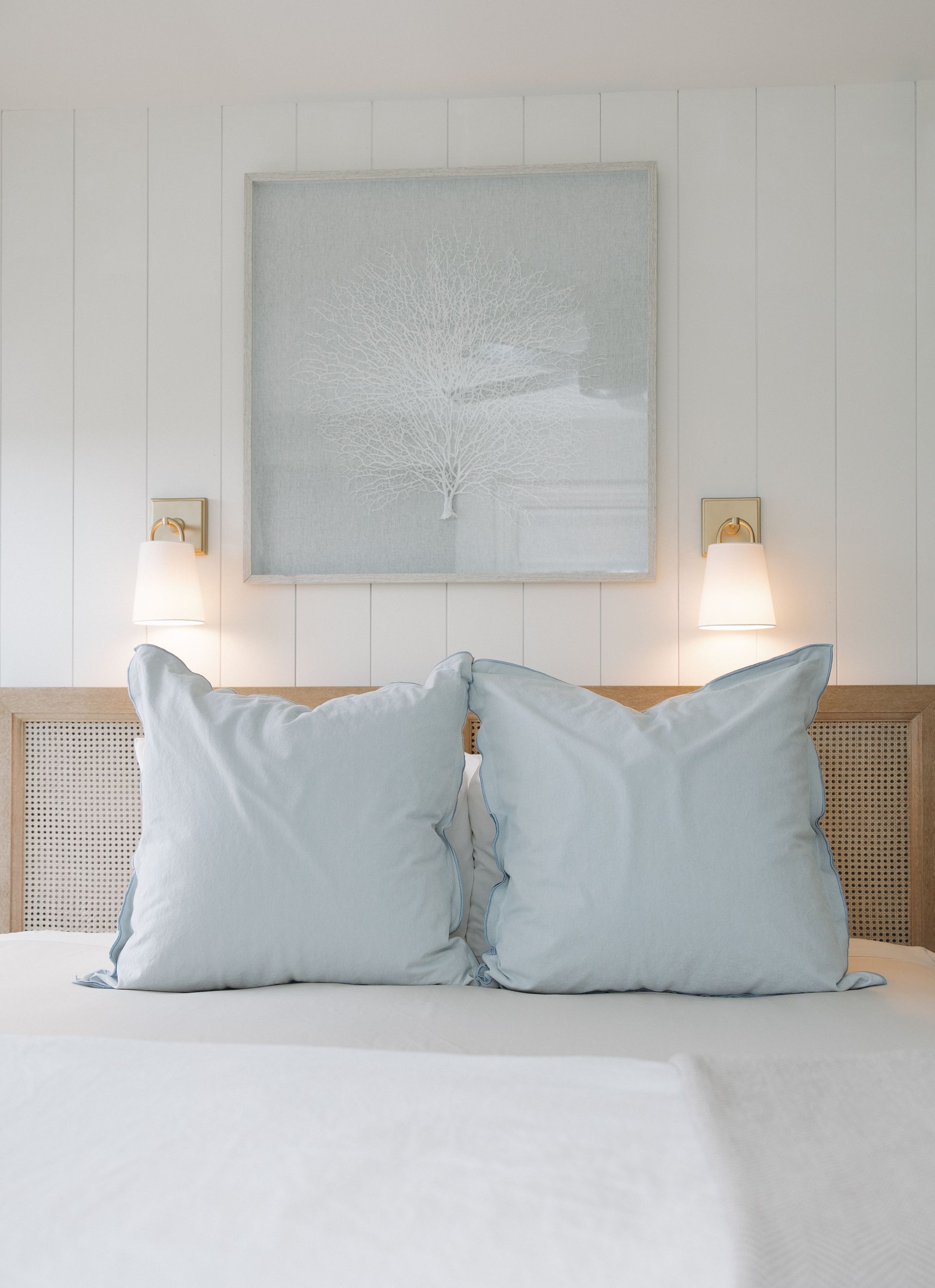 A bedroom with a painting on the wall above the bed