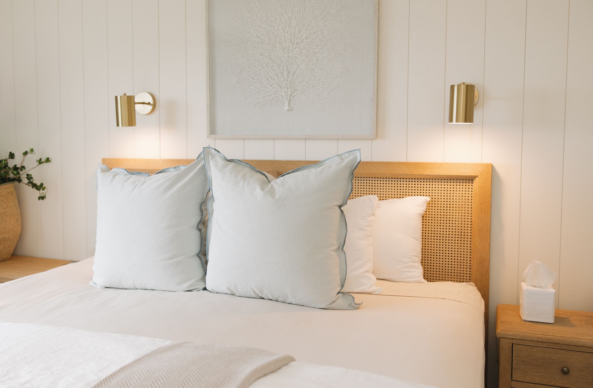 A bedroom with a bed , pillows , blankets and a basket on the bed.