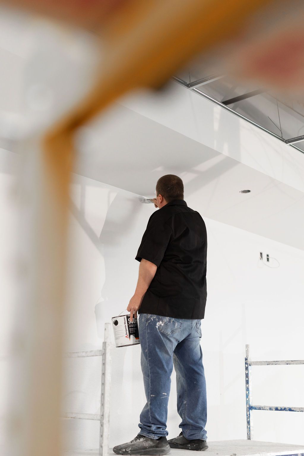 A man is holding a flashlight and looking up at a wall.