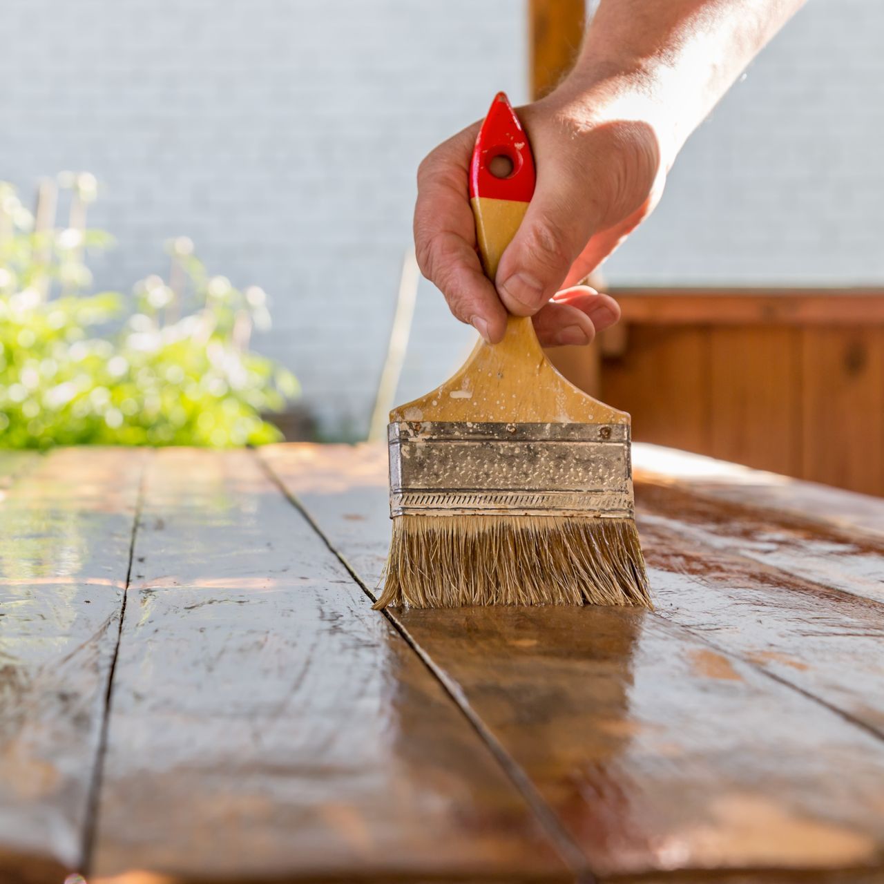 A person is painting a wooden table with a brush.