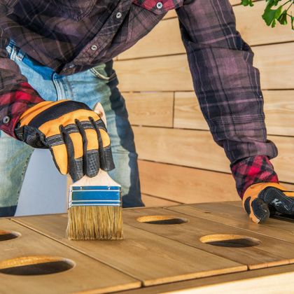 A man is painting a wooden table with a brush