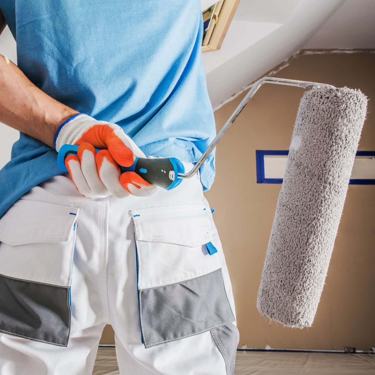 A man in a blue shirt is holding a paint roller