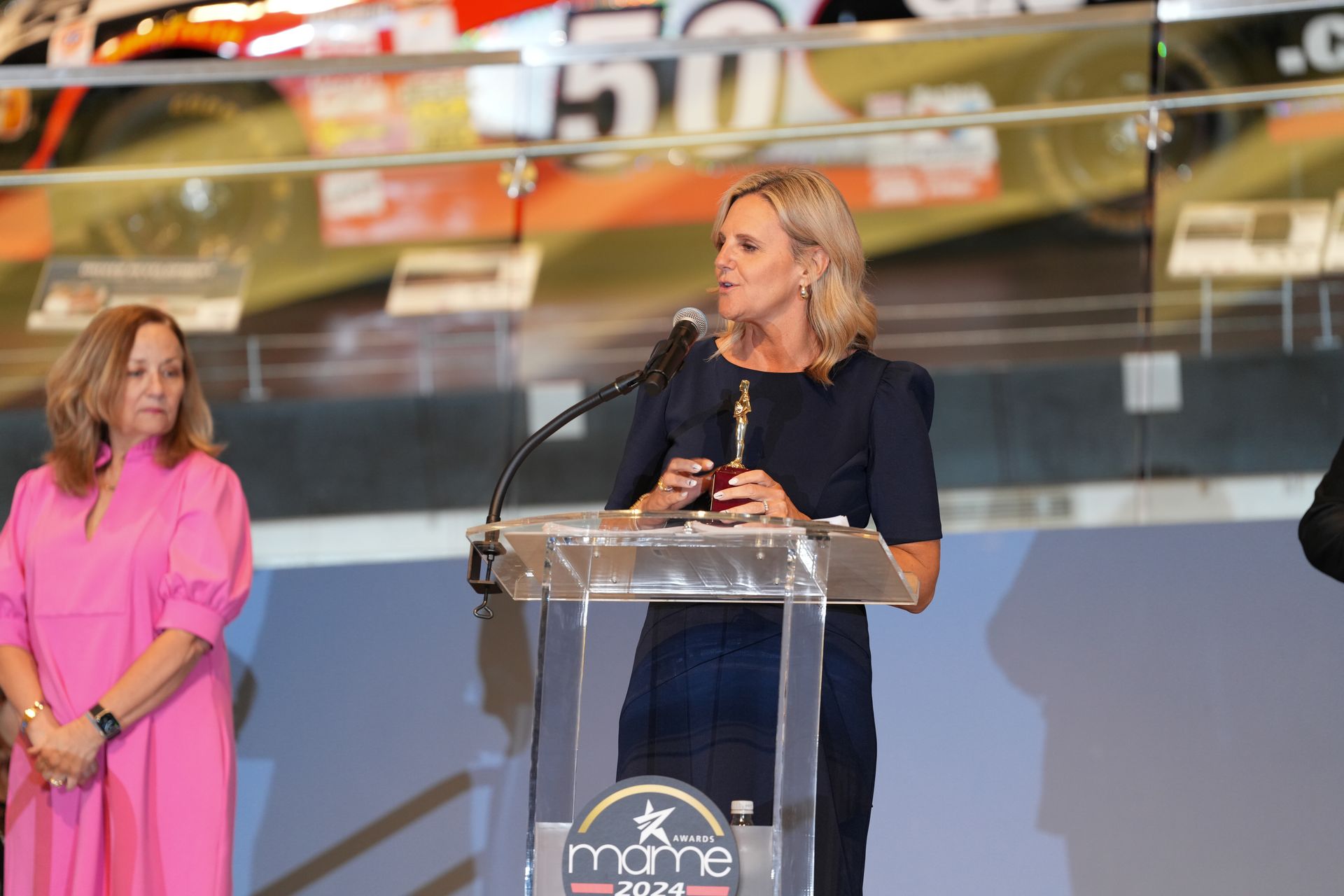 A woman is standing at a podium speaking into a microphone.