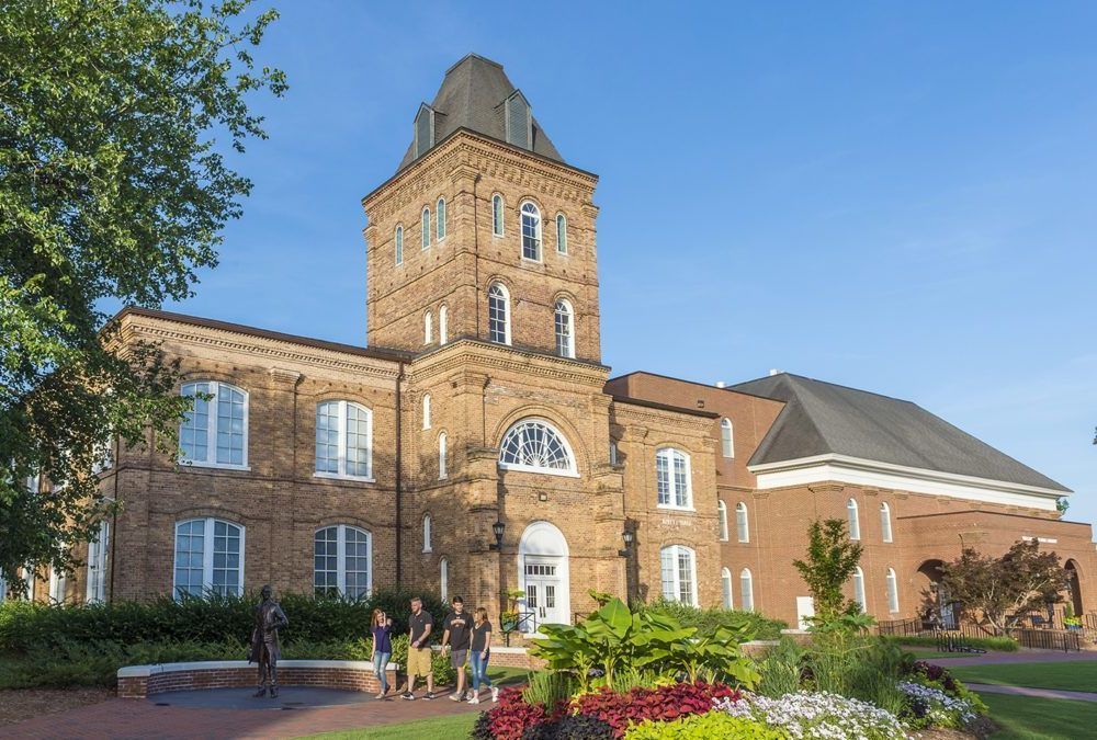 A group of people are standing in front of a large brick building.