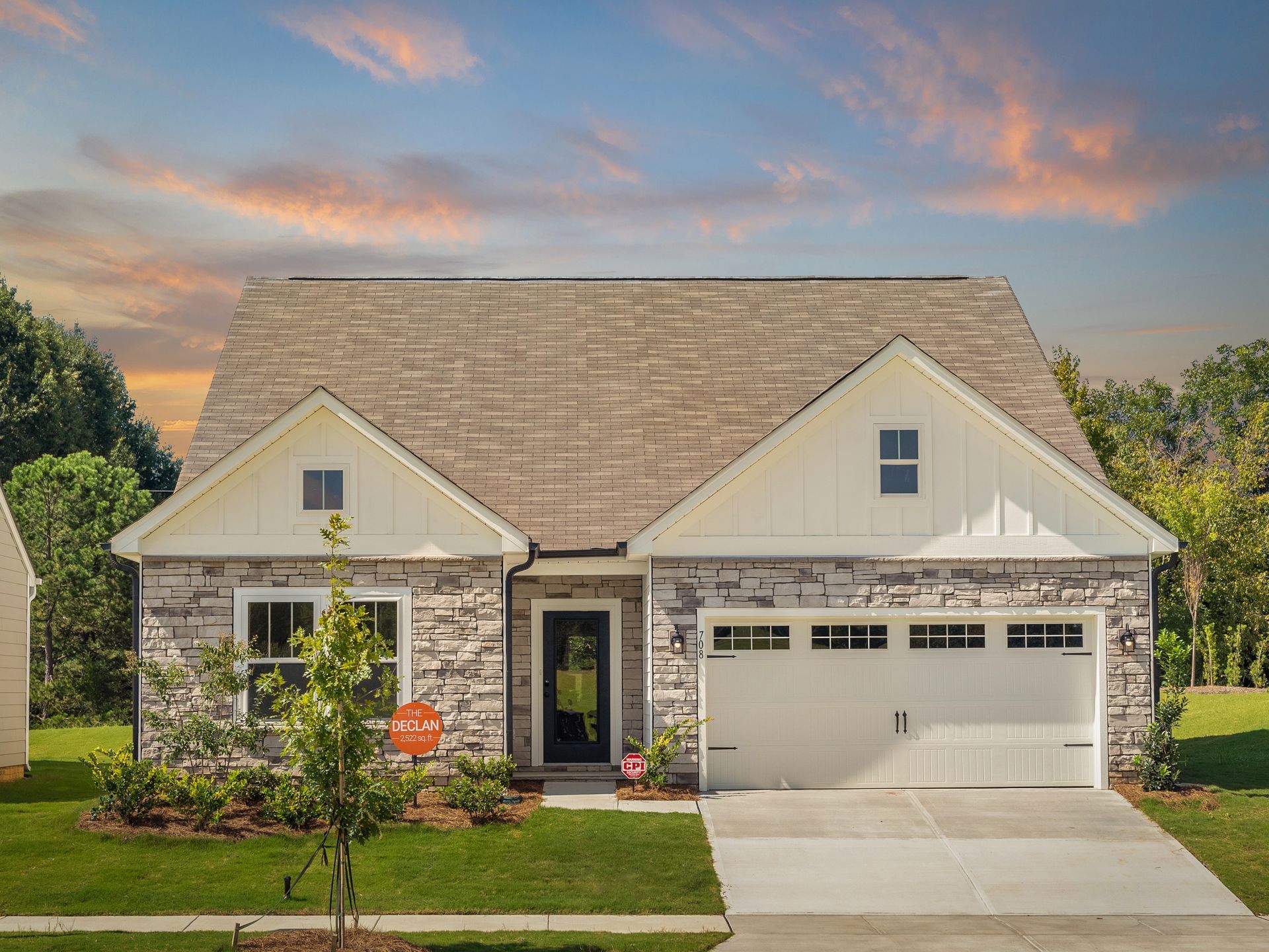 A white house with a brown roof and a white garage door.