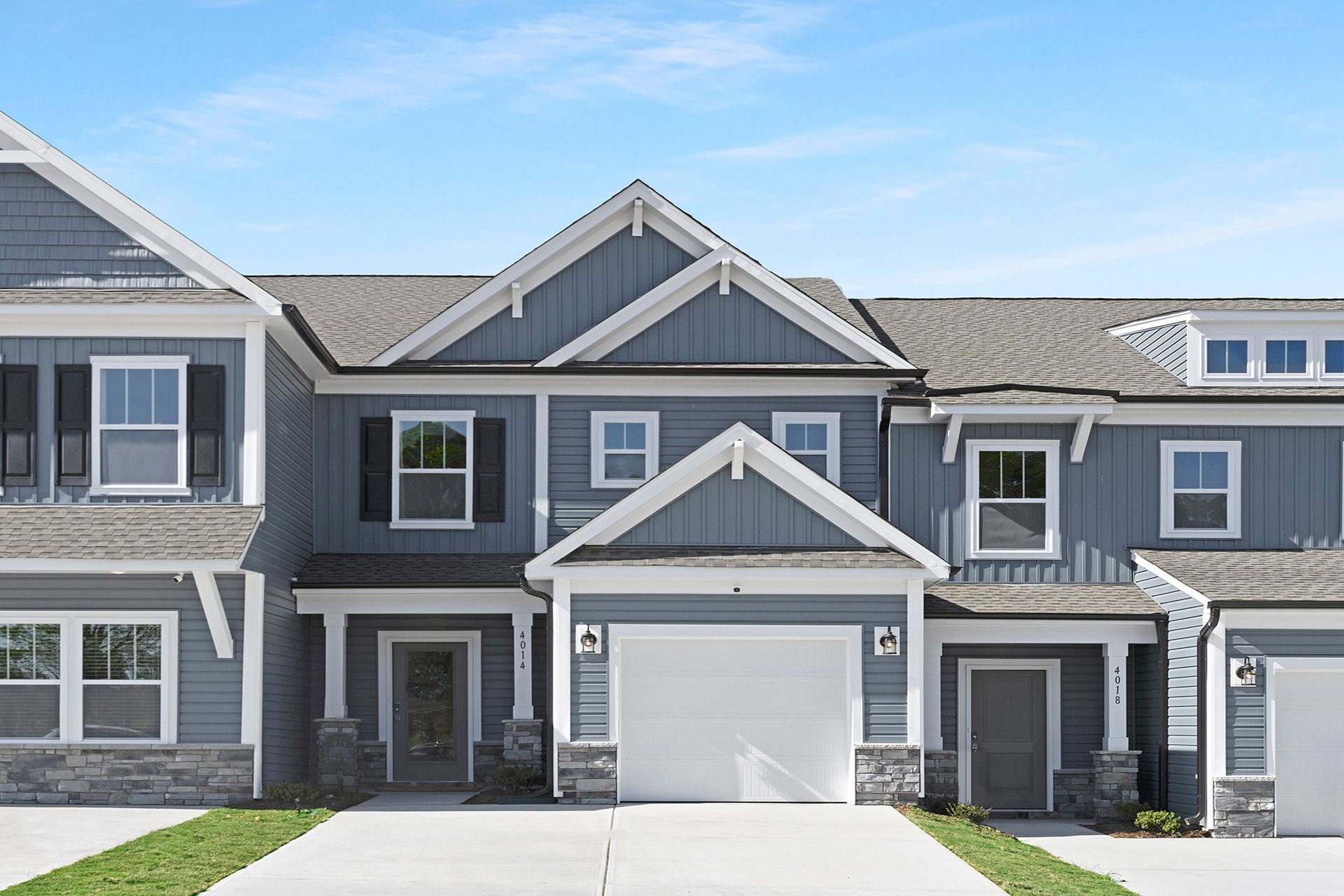 Blue townhouses with white trim, gray stone accents, and white garage doors.