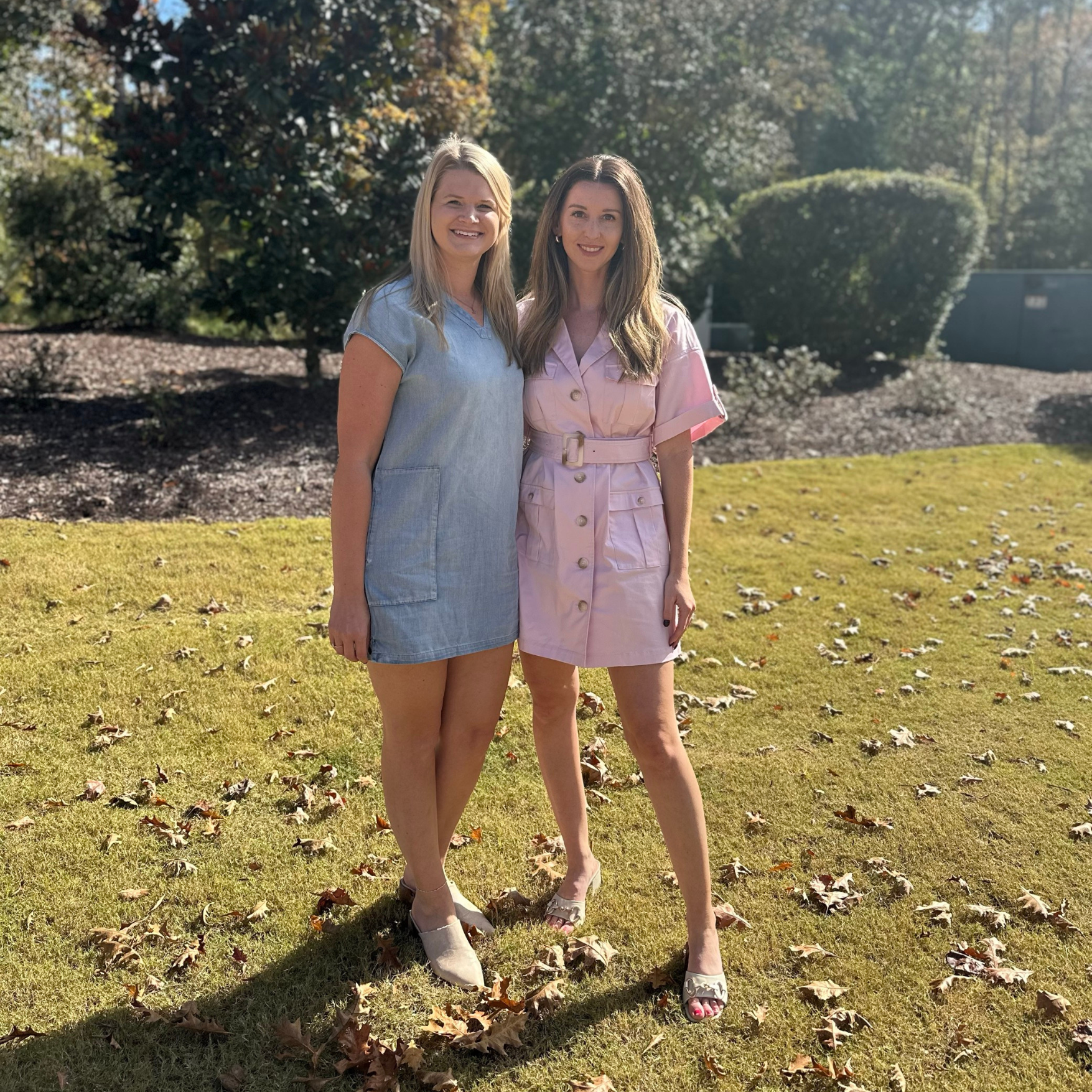 Two women standing next to each other in a grassy field