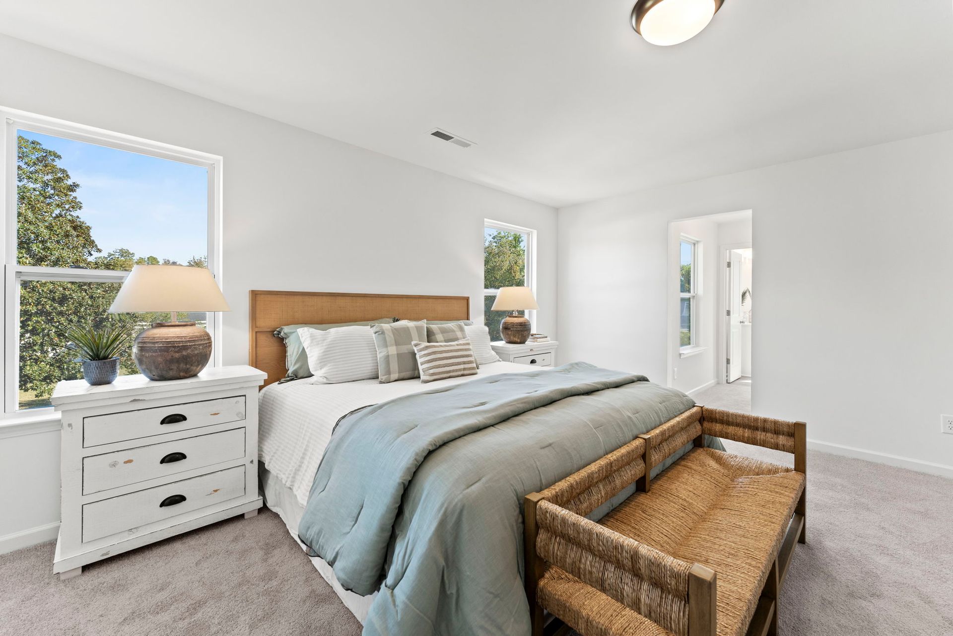 A bedroom with a bed , dresser , nightstand and bench.