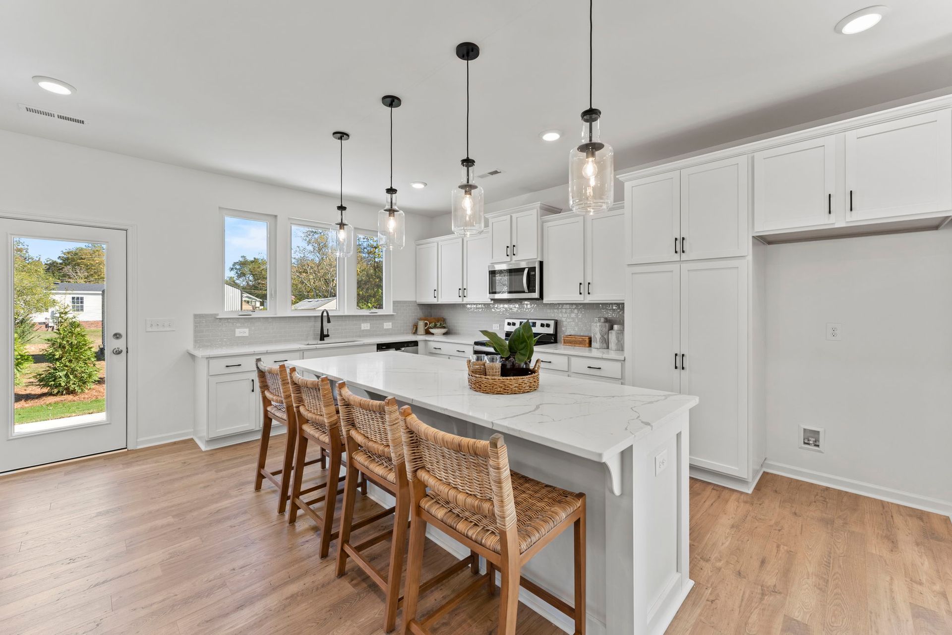 A kitchen with white cabinets , a large island , and wooden floors.
