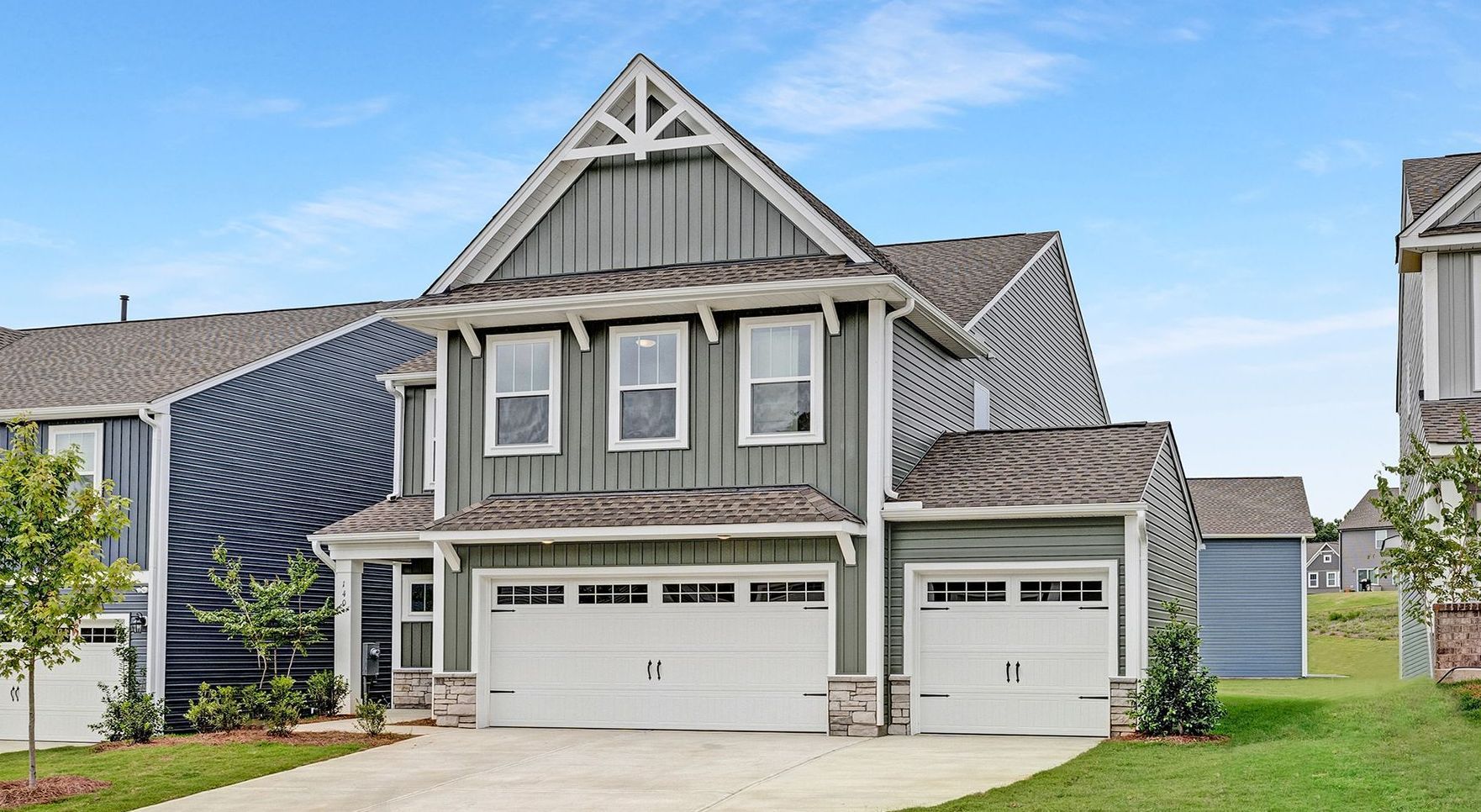 Two-story house with gray siding, two-car garage, and blue sky.