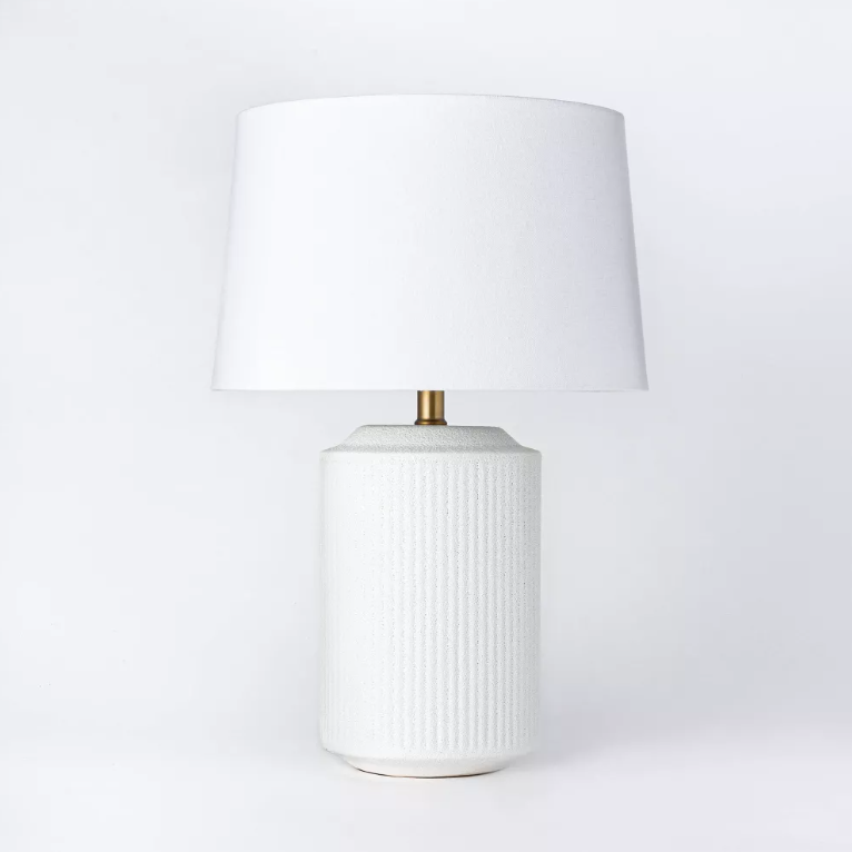 A white table lamp with a white shade on a white background.