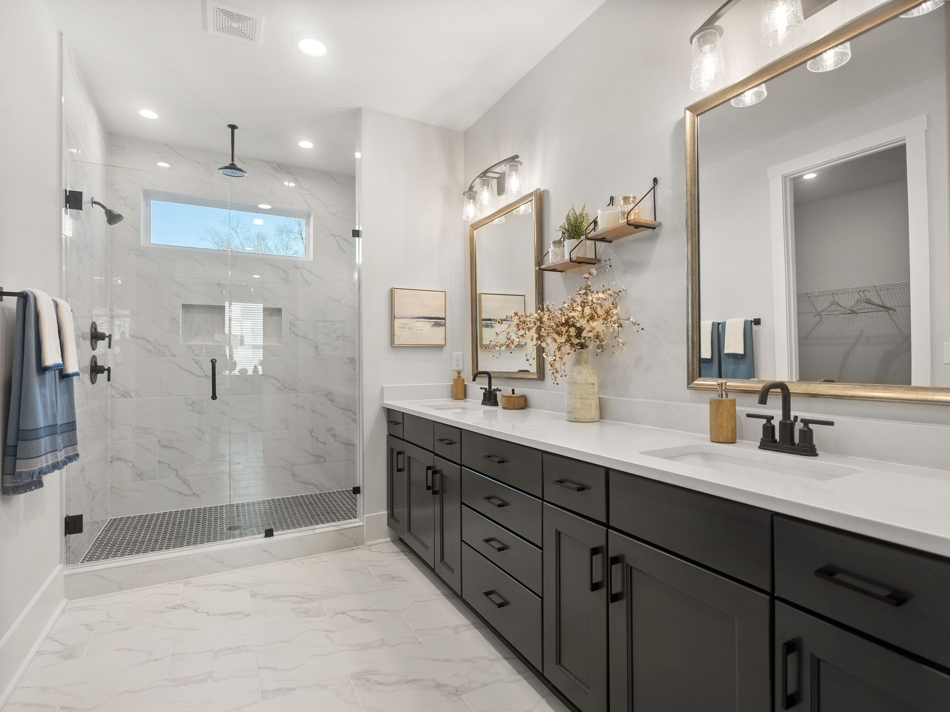 A bathroom with two sinks , two mirrors and a walk in shower.