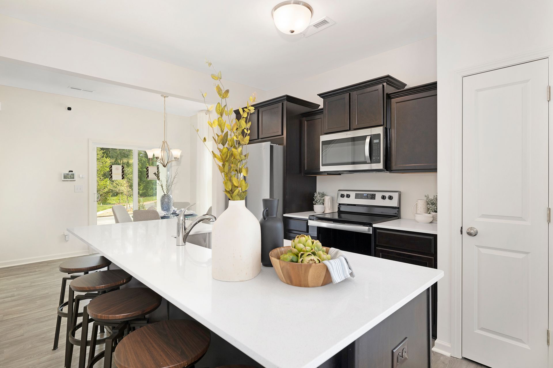 A kitchen with white counter tops , black cabinets , stainless steel appliances and a large island.