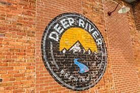 A brick wall with a painting of a river and mountains on it.