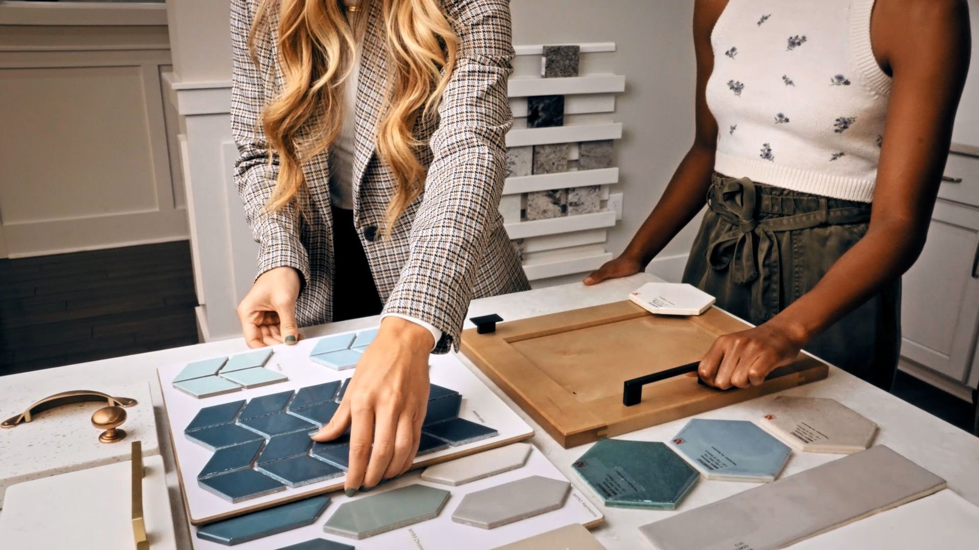 Two women are looking at tiles on a table.