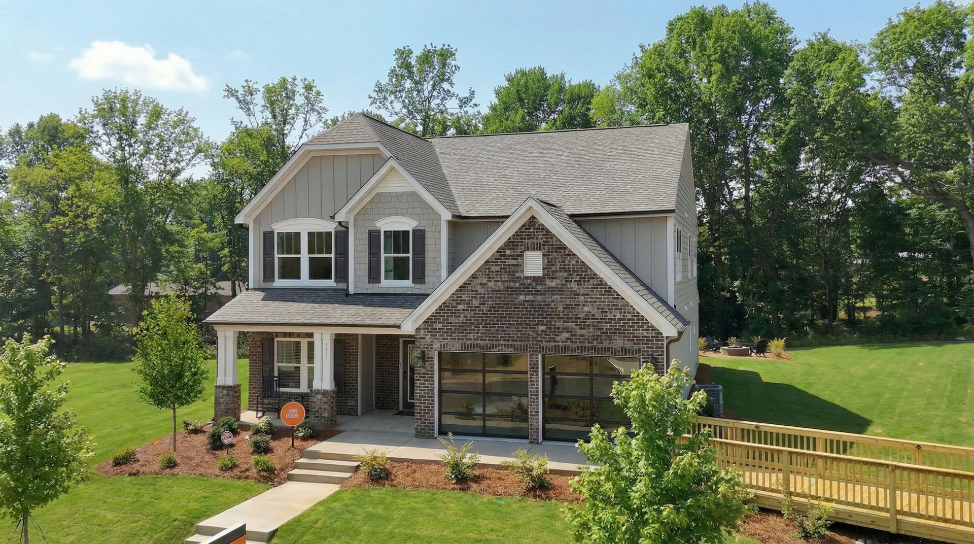 Two-story house with blue siding, stone facade, and a green lawn on a sunny day.