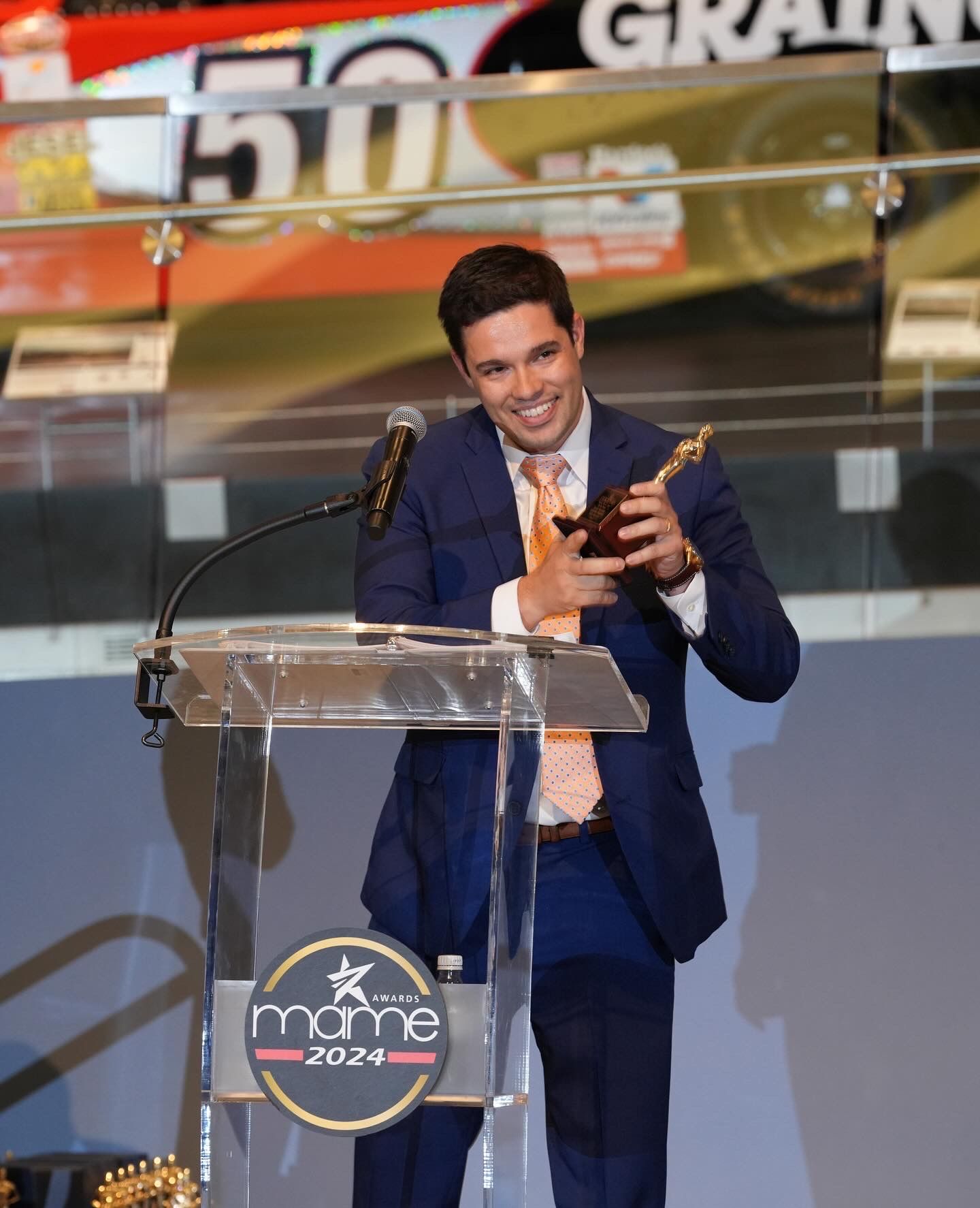 A man in a suit and tie is standing at a podium holding a trophy