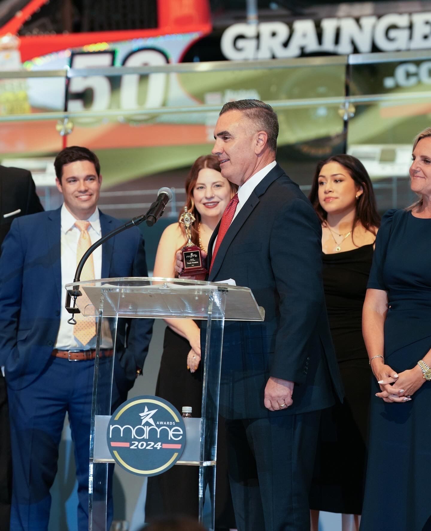 A group of people standing around a podium that says graine on it
