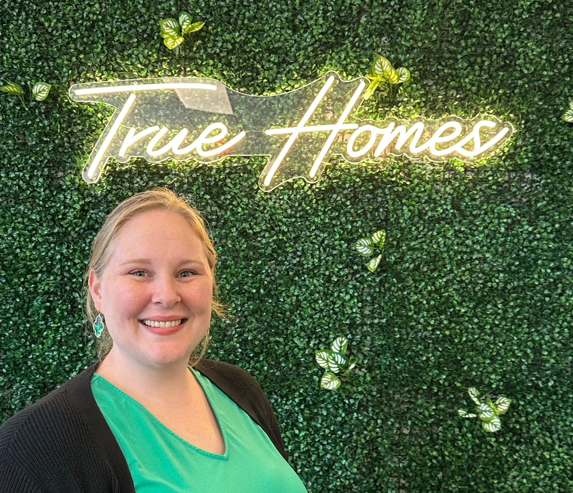 Woman smiling in front of a green wall with neon