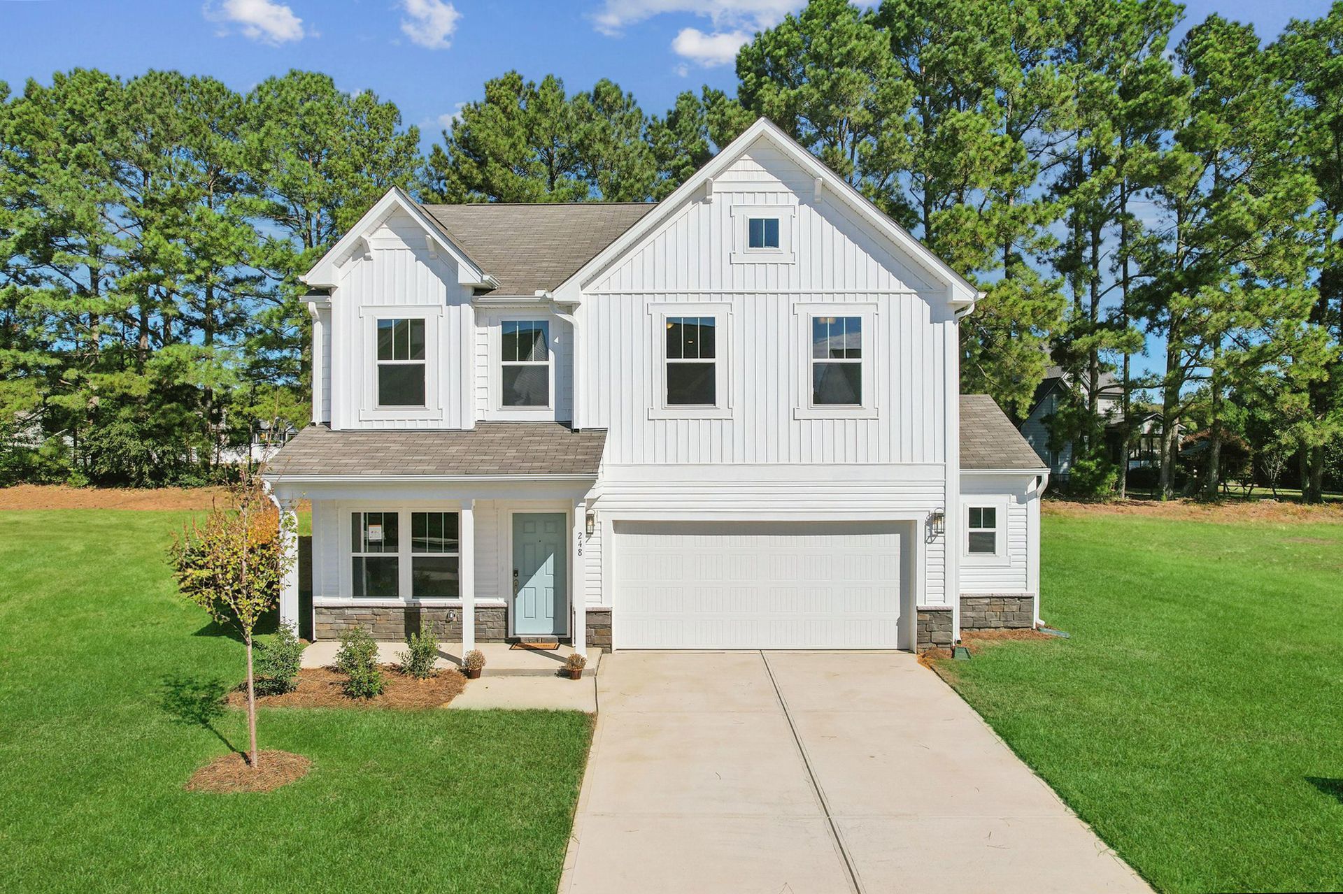 White two-story house with a gray roof, blue front door, and attached garage, set on a grassy lawn.