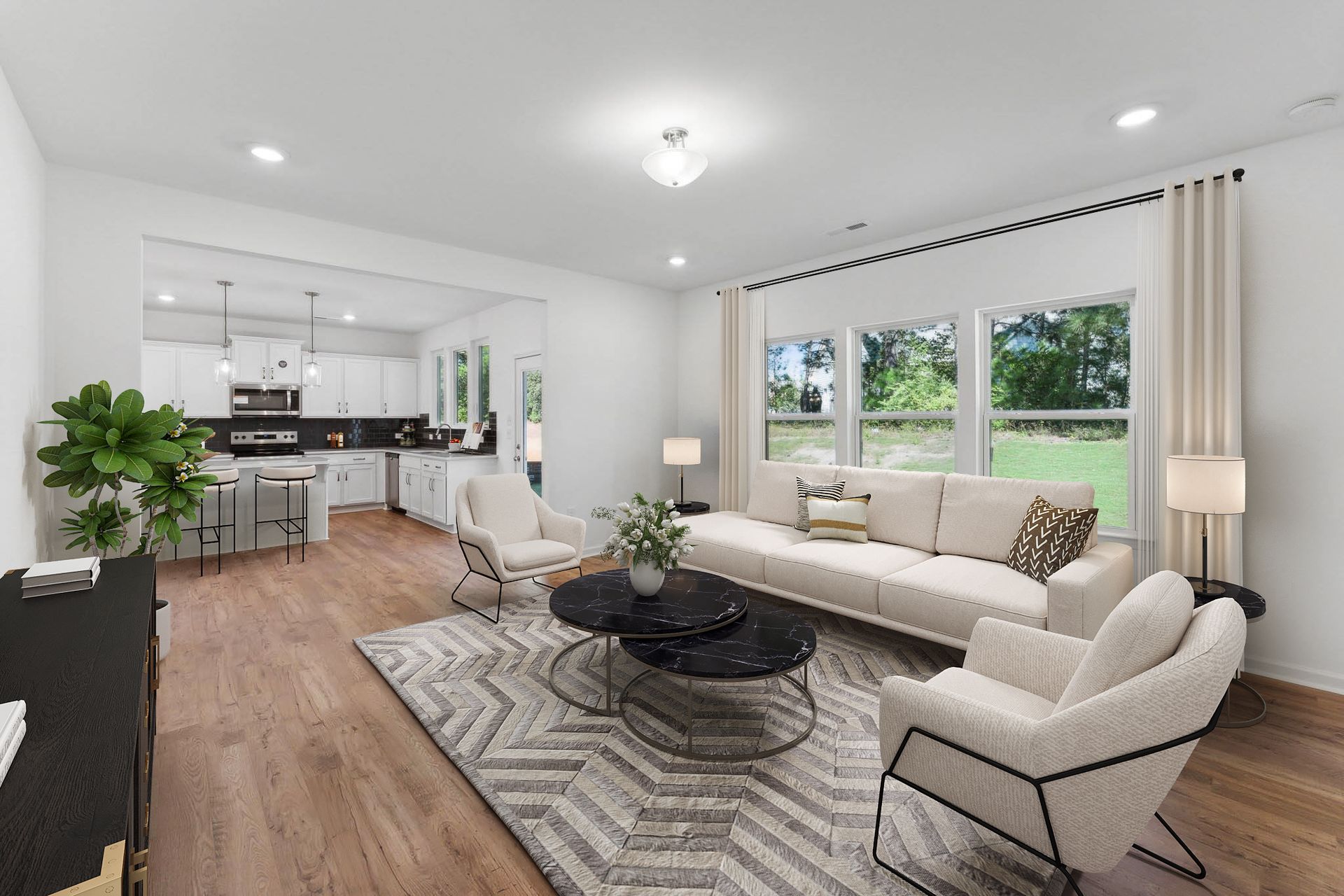 Living room with open kitchen; white walls, light wood floors, neutral furniture, large windows.