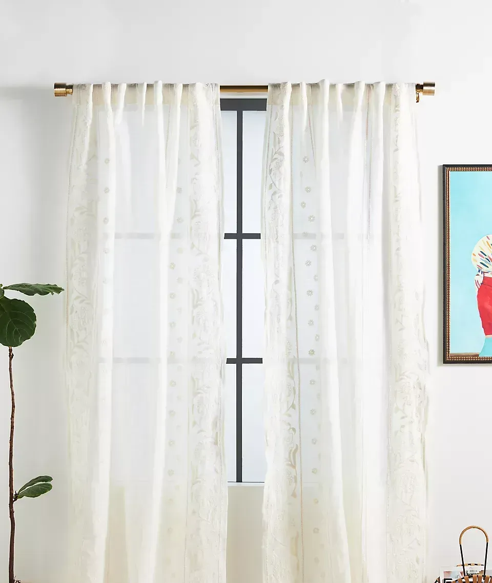 A window with white curtains and a picture on the wall