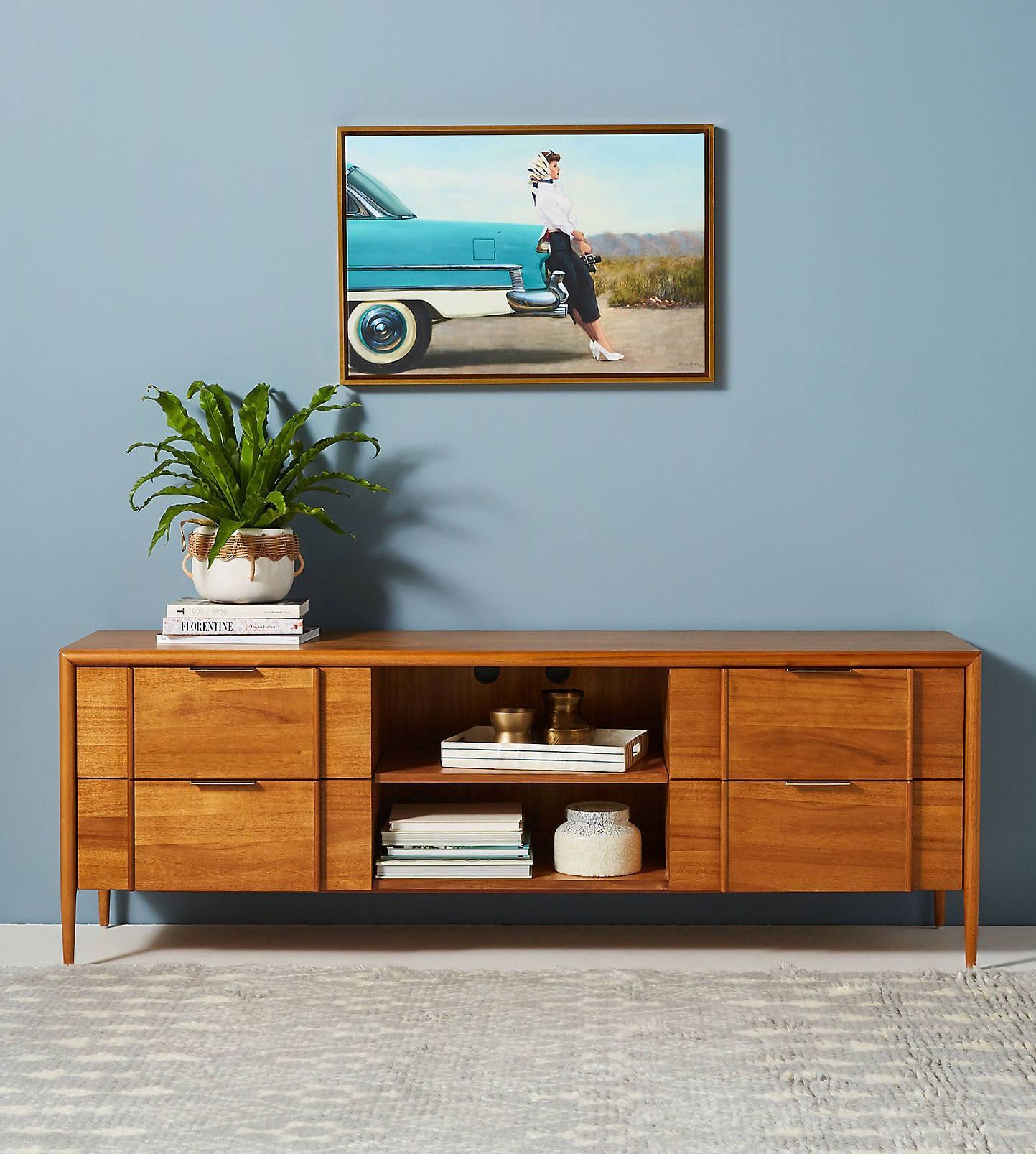 A picture of a car is hanging on a wall above a wooden dresser