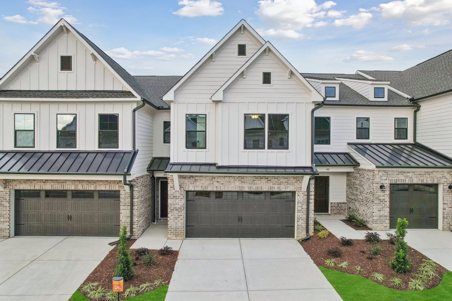 Two-story house with blue siding, stone facade, and a green lawn on a sunny day.
