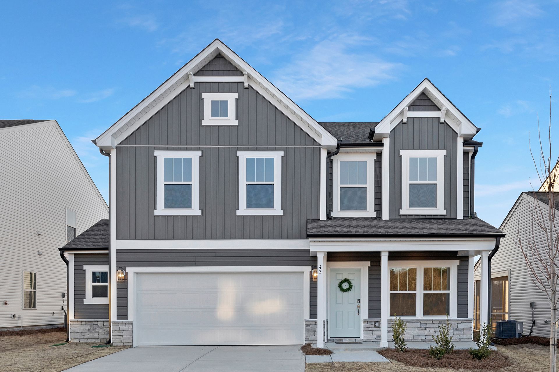 Gray two-story house with white trim, blue door, and a green wreath.
