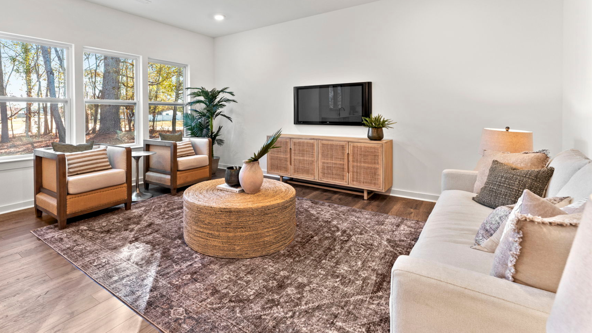 A living room with a couch , chairs , coffee table and television.