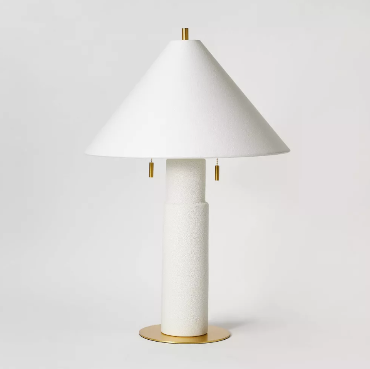A white lamp with a cone shaped shade and a brass base